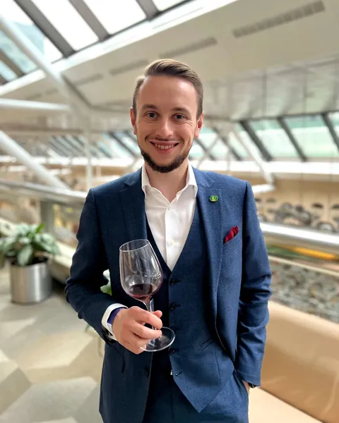 Portrait of Nikita Khudov holding a glass of red wine